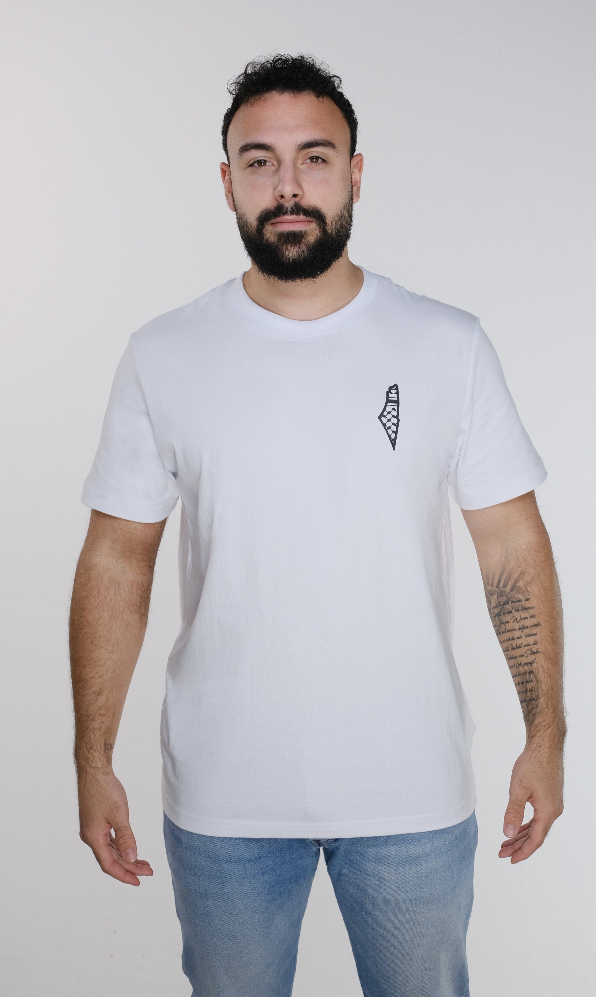 Front view of the model wearing the white Palestine Brand Logo T-shirt, featuring a minimalist design with a small map of Palestine on the right chest. The logo is inspired by the colors of the traditional keffiyeh. The back of the T-shirt is plain white.