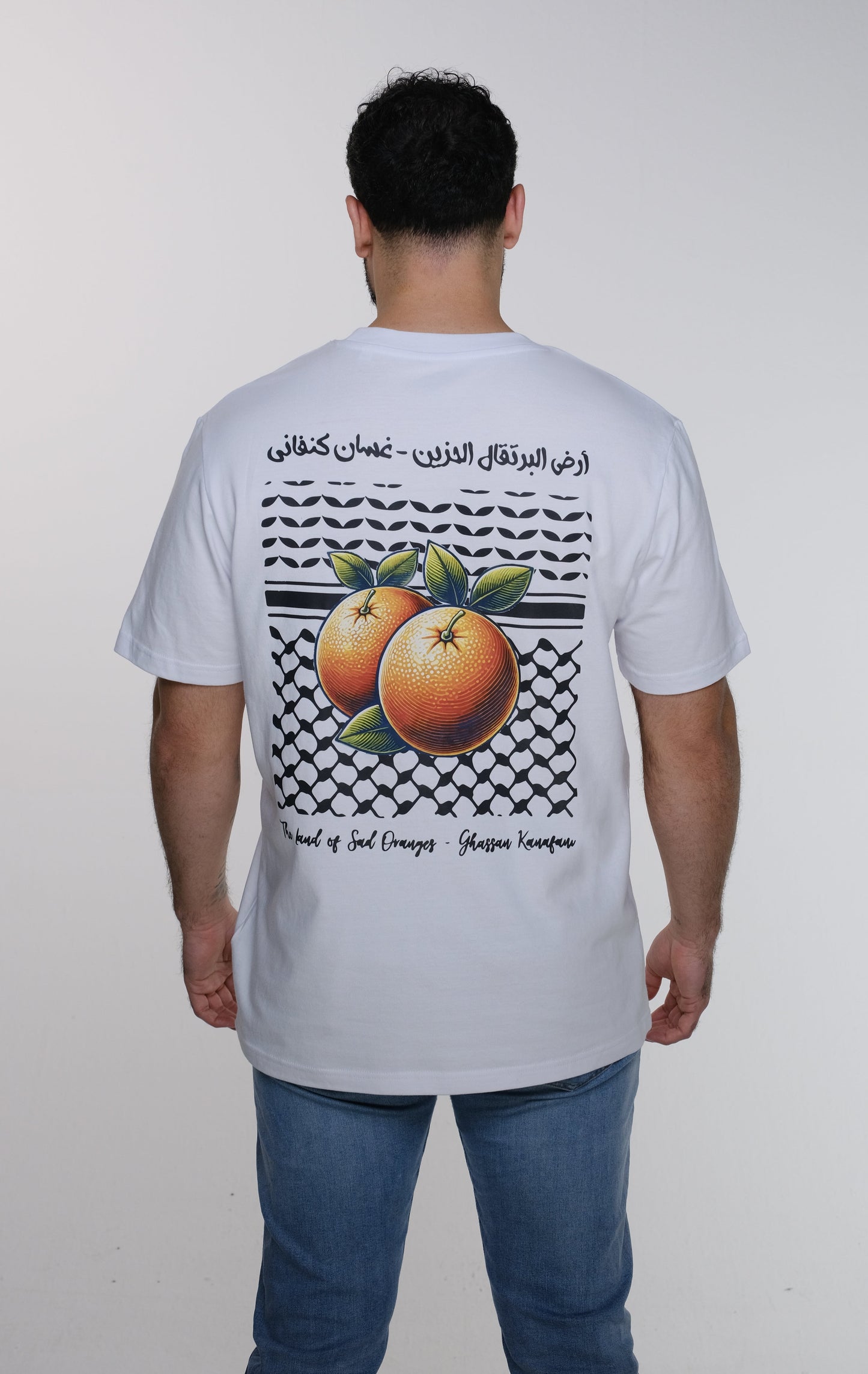 Model showing the back of the Ghassan Kanafani t-shirt with the prominent square design combining the Palestinian keffiyeh and poetic calligraphy.