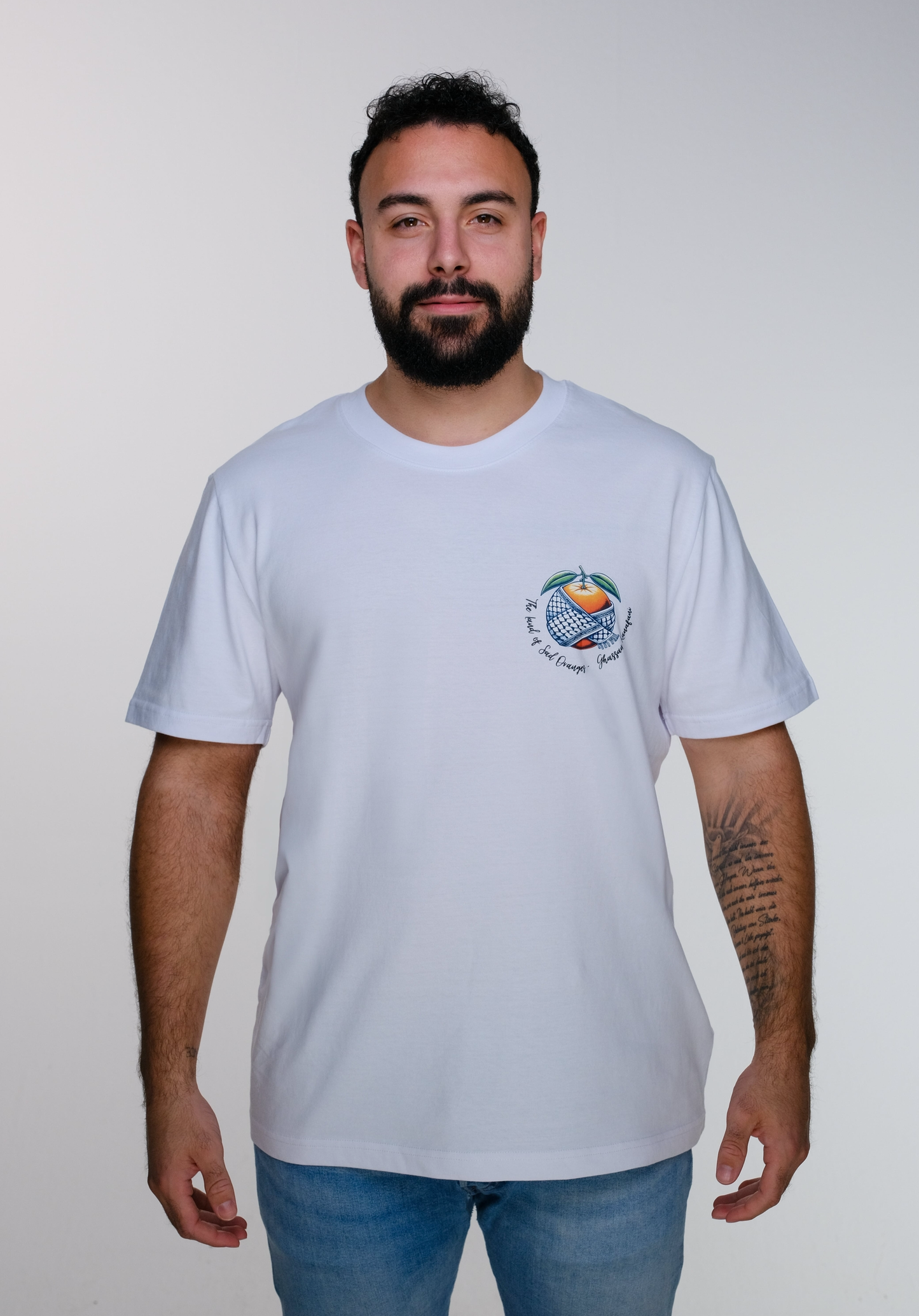 Model wearing the Ghassan Kanafani t-shirt, front view, displaying the minimalist chest design with the symbolic orange wrapped in a keffiyeh.