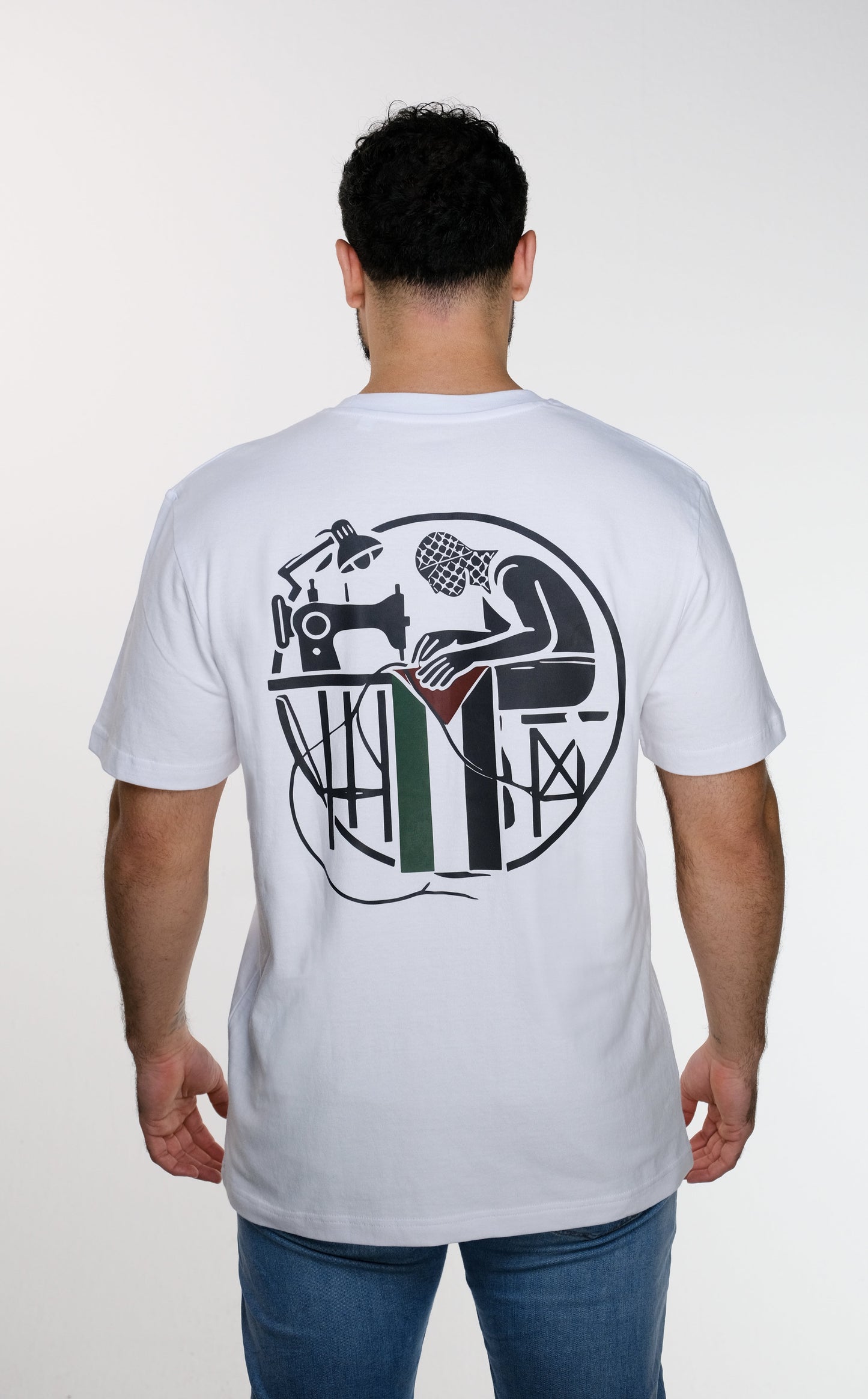 Back view of model wearing the Khayyat T-shirt, featuring a circular artwork of a Palestinian sewing the Palestinian flag, with a keffiyeh wrapped around his head — a tribute to self-reliance and identity.