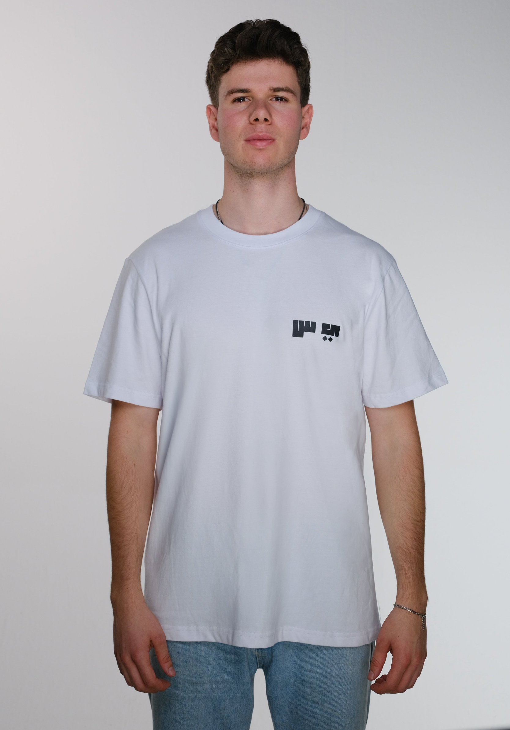 Front view of model wearing a white Resist T-shirt, featuring the Arabic letters "ي" and "س" subtly printed on the right chest, symbolizing resistance.